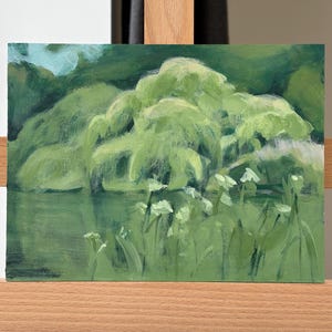 May include: An oil painting on canvas depicting a landscape scene with a large, weeping willow tree in shades of light and dark green. The tree hangs over a calm body of water, with white wildflowers in the foreground and a hint of blue sky above.
