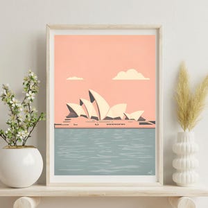 Può includere: Stampa artistica incorniciata con un'illustrazione stilizzata della Sydney Opera House. L'opera d'arte mostra l'edificio iconico con vele bianche contro un cielo color pesca e acqua blu. Due nuvole bianche nel cielo.