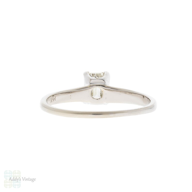May include: A simple solitaire engagement ring with a single, round, prong-set diamond. The ring is made of white gold and has a polished finish.