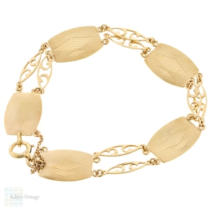 May include: A vintage gold-toned bracelet featuring six rectangular links with etched chevron patterns. The links are connected by delicate, openwork filigree sections. A small chain and clasp secure the bracelet, showcasing a classic design.