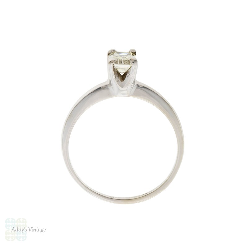 May include: A silver solitaire engagement ring with a square-shaped diamond.