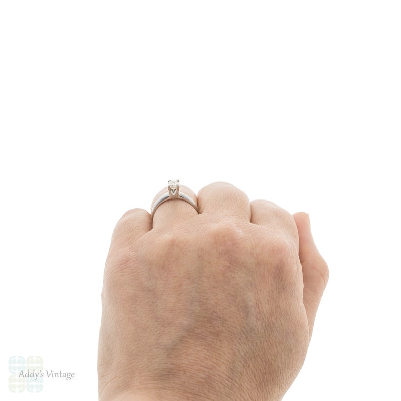 May include: A silver ring with a single, clear diamond set in a prong setting.