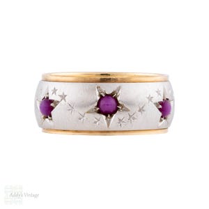 Può includere: Un anello vintage con fascia argentata e finiture dorate. La fascia presenta ritagli a forma di stella, ciascuno con una gemma rotonda viola. Stelle più piccole sono incise attorno a quelle più grandi, creando un design celeste.