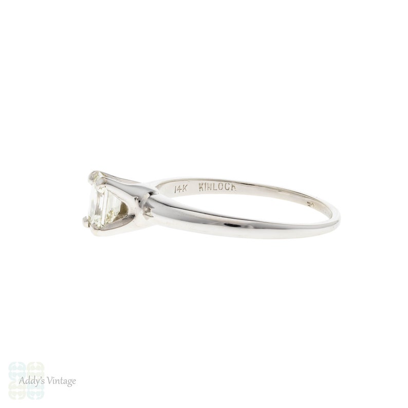 May include: A 14k white gold engagement ring with an emerald cut diamond. The ring is marked "Kinloca" on the inside of the band.