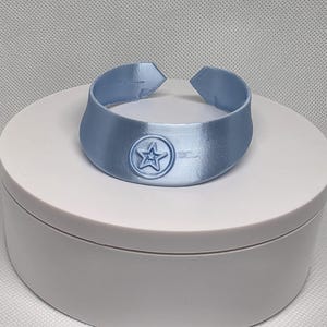 Op de afbeelding: Een lichtblauwe plastic choker ketting met een vijfpuntige ster ontwerp.