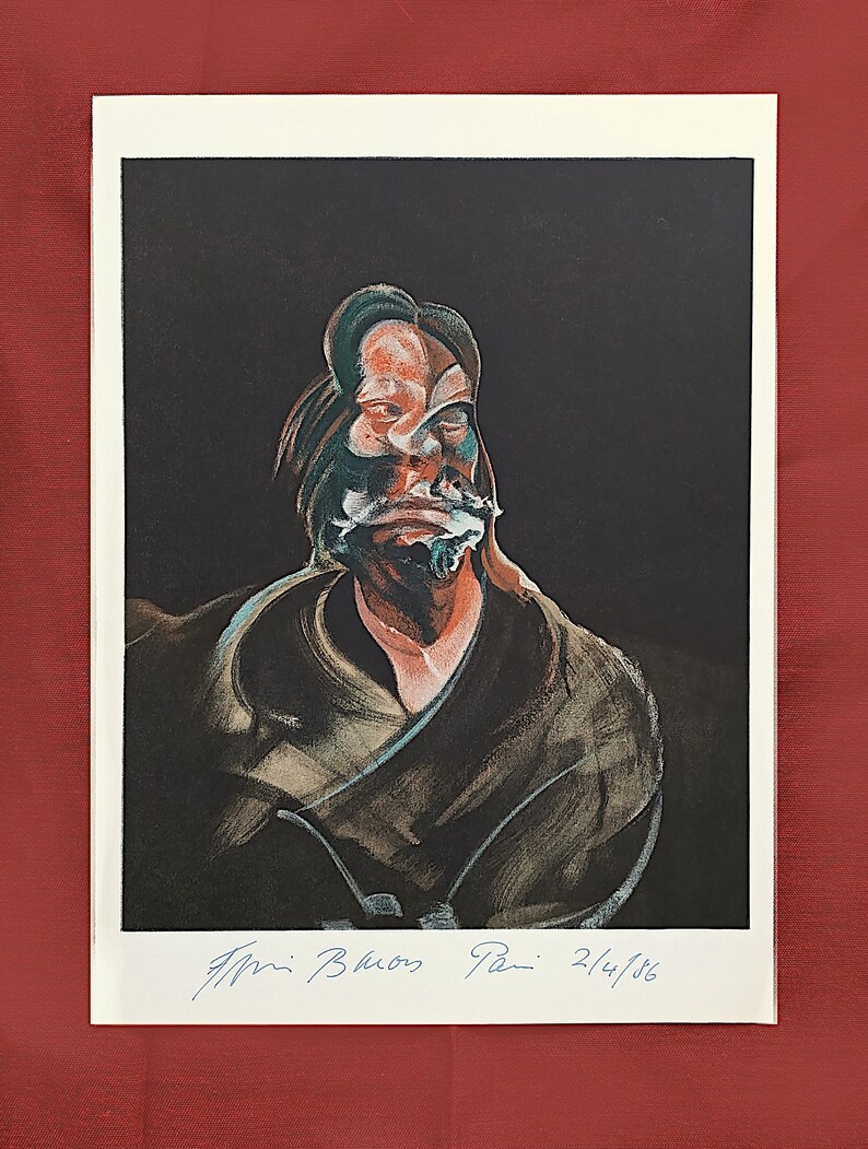 May include: A framed print of a portrait with a dark backdrop. The artwork shows a distorted face in shades of orange, green, and white. The print is signed and dated "2/4/86" in blue ink. The frame is white, and the background is a deep red.