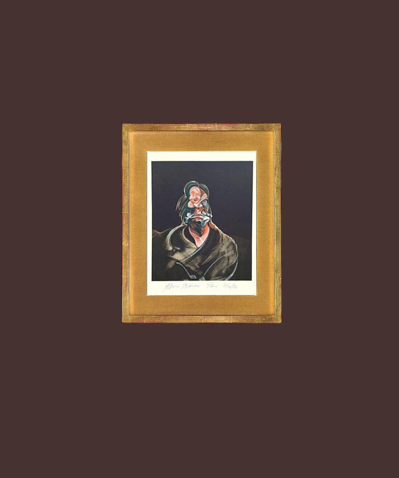 May include: Framed artwork with an abstract portrait on a black background, set within a gold-coloured frame. The artwork features a signed signature at the bottom. The overall aesthetic is dark and artistic.
