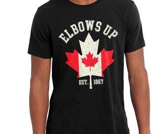 May include: Black t-shirt with a white distressed graphic of a Canadian flag maple leaf with the text "Elbows Up" and "Est. 1867" underneath.