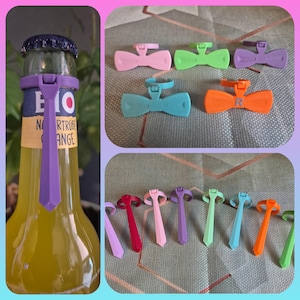 Könnte beinhalten: Eine Sammlung farbenfroher Flaschenaccessoires, darunter Fliegen und krawattenförmige Designs, in verschiedenen Farbtönen wie Rosa, Grün, Lila und Orange. Eines ist an einer Flasche Orangensaft befestigt. Die Accessoires sind aus Kunststoff.