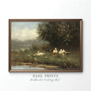May include: A framed landscape painting depicting a group of white ducks resting in tall green grass near a calm body of water, with dark trees in the background under a cloudy sky. The text DAHL PRINTS Authentic Vintage Art is below.