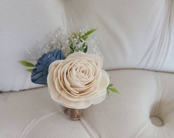 May include: A small bouquet of white and blue flowers with a burlap bow. The bouquet is made of wood and is perfect for a wedding or other special occasion.