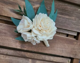 May include: A small bouquet of white sola wood flowers with green leaves. The flowers are arranged in a cluster and have a delicate, romantic look.