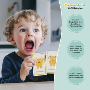 May include: A young child with wide eyes and an open mouth holds two yellow cards with cartoon monster illustrations. The cards have German text. The background includes text about feelings and family.