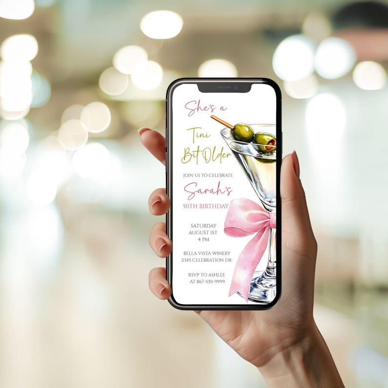 May include: A smartphone screen shows a digital invitation for a 50th birthday celebration. The design includes a martini glass with olives, a pink bow, and the text "She's a Tini Bit Older." The invitation provides event details and RSVP information.