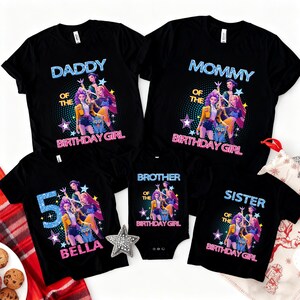 Op de afbeelding: Zwarte t-shirts en een romper met een kleurrijk grafisch ontwerp. De shirts lezen "Daddy", "Mommy", "Brother" en "Sister" met "Of The Birthday Girl". E&eacute;n shirt zegt "5 BELLA".
