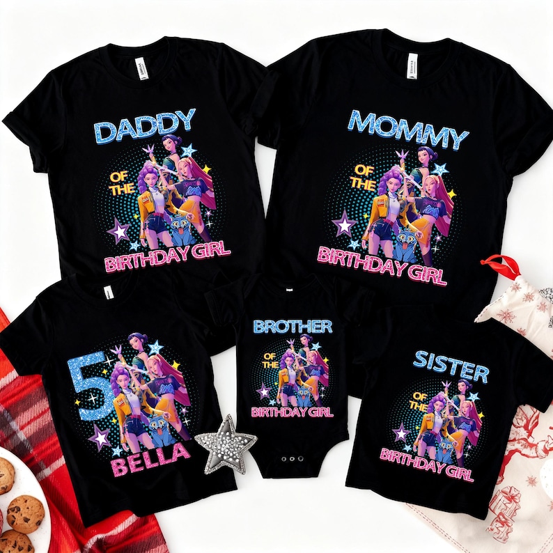 Op de afbeelding: Zwarte t-shirts en een romper met een kleurrijk grafisch ontwerp. De shirts lezen "Daddy", "Mommy", "Brother" en "Sister" met "Of The Birthday Girl". E&eacute;n shirt zegt "5 BELLA".