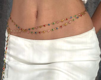 May include: A gold chain body jewelry with colorful heart-shaped charms. The chain is layered and has a delicate design.
