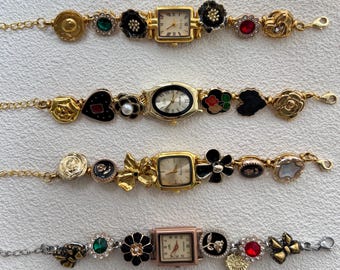 May include: Four gold charm bracelets with different colored watch faces and various charms, including flowers, hearts, and stars.