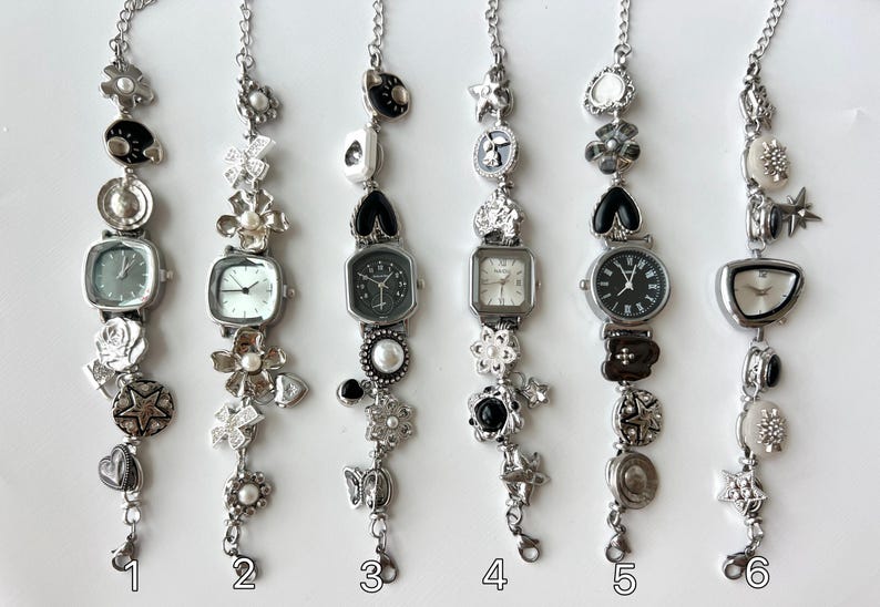 May include: Six silver charm bracelets, each with a different watch face and decorative charms. The bracelets feature square and round watch faces, and are adorned with charms such as stars, flowers, and hearts. They are displayed against a white background.