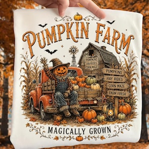 May include: A white t-shirt featuring a graphic of a pumpkin-headed scarecrow sitting in an orange truck. The text reads PUMPKIN FARM and MAGICALLY GROWN, with illustrations of a barn, corn stalks, pumpkins, and a lantern in autumn colors.