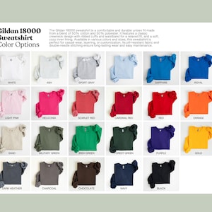 May include: A display of Gildan 18000 sweatshirts in various colors, including white, ash, sport gray, sapphire, royal, light pink, and more. The image shows the color options available for the sweatshirt.
