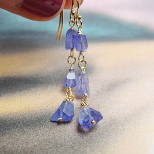 May include: Gold dangle earrings with multiple blue gemstone drops.