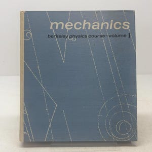 May include: A blue hardcover textbook titled Mechanics Berkeley Physics Course Volume 1. The front cover features white geometric line drawings, including straight lines and concentric circles, set against a solid blue background.