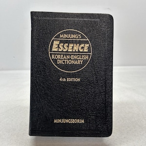 May include: A black hardcover book titled Minjung's Essence Korean-English Dictionary 4th Edition. The cover features a textured surface with gold lettering enclosed in a circular border, with the publisher name Minjungseorim at the bottom.