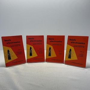 May include: Four softcover books titled Basic Electronics by Van Valkenburgh, Nooger & Neville, Inc. Each book has a bright orange cover with a yellow triangle, a black obelisk graphic, and an atom symbol. The volumes are labeled Vol. 1 through Vol. 4.