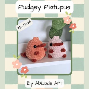 May include: A crochet pattern cover featuring two plush platypus toys in shades of orange and pink. The text "Pudgey Platupus" is displayed above the toys, with "No-Sew!" and "By Abijade Art" also visible. The background has a checkered pattern.