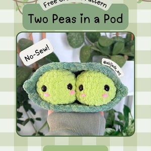 May include: A crochet pattern titled Free Crochet Pattern Two Peas in a Pod by AbiJade Art. The image features two round, light green plush peas with black eyes and pink cheeks nestled inside a textured, dark green crochet pod. Text reads No-Sew!