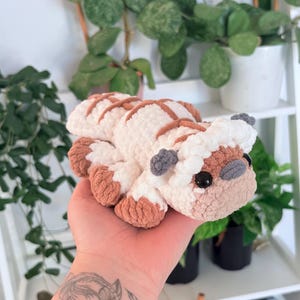 Puede incluir: Un peluche de ganchillo hecho a mano con forma de criatura, con cuerpo blanco, marcas marrones y orejas grises. El juguete tiene ojos negros y un hocico marr&oacute;n claro. Un juguete suave y tierno para ni&ntilde;os o coleccionistas.