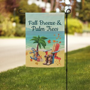 May include: A garden flag with the text "Fall Breeze & Palm Trees" features a beach scene with a palm tree, anchor, pumpkins, cowboy boots, and a red and yellow Adirondack chair. The flag is displayed on a black metal garden stake.
