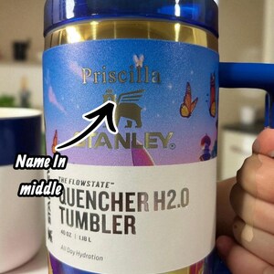 May include: A blue and gold Stanley Quencher H2.0 tumbler with a handle. The tumbler has the name "Priscilla" printed on it, along with the Stanley logo and the words "QUENCHER H2.0 TUMBLER". It holds 40 oz (1.18 L).