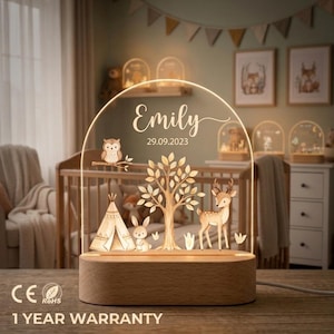 Op de afbeelding: Een boogvormig acryl nachtlampje met een houten voet, voorzien van een bosscène met een tipi, een boom, een konijn, een hert en een uil. De tekst Emily en 29.09.2023 staat in het midden. Het lampje geeft een warme gloed vanaf de voet.