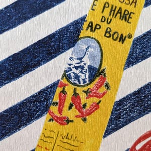 Zoom sur l'illustration. Dessin d'un tube de harissa sur un fond à rayures bleu et blanc. L'illustration est dessinée aux crayons de couleurs. Elle présente également des tomates, piments, ail et coriandre et un plat à motifs, suggérant une ambiance tunisienne. L'illustration est signée de Lucie Leforestier et numérotée, en édition limitée. Le papier est texturé.