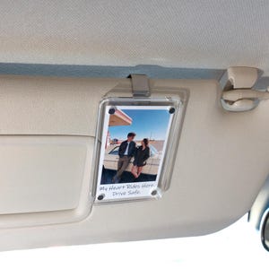 Könnte beinhalten: Transparenter Acryl-Fotohalter mit Metallclip, der ein Foto eines Paares an einem Oldtimer an einer Tankstelle zeigt. Der Text "My Heart Rides Here. Drive Safe." ist auf dem Foto aufgedruckt.