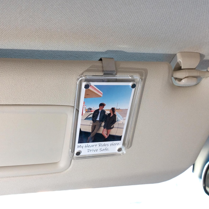 May include: Clear acrylic photo holder with a metal clip, displaying a photo of a couple by a vintage car at a gas station. The text "My Heart Rides Here. Drive Safe." is printed on the photo.