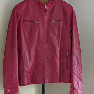 Op de afbeelding: Een rood leren jack met een ritssluiting en meerdere zakken.