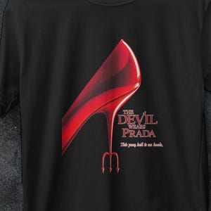 Könnte beinhalten: Schwarzes T-Shirt mit einer roten High-Heel-Schuh-Grafik und dem Text "The Devil Wears Prada". Das Design beinhaltet einen Dreizack und den Satz "This party shall be no fun."