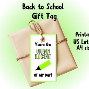 May include: A gift wrapped in brown paper with a twine bow, featuring a green and white gift tag. The tag reads "You're the HIGHLIGHT OF MY DAY!" with a highlighter illustration. Text at the top says "Back to School Gift Tag."