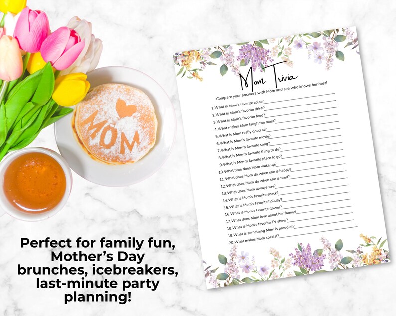May include: A Mother's Day brunch scene with pancakes dusted with powdered sugar spelling "MOM" and a heart, a cup of orange juice, and a "Mom Trivia" game sheet with floral accents. Tulips add colour.