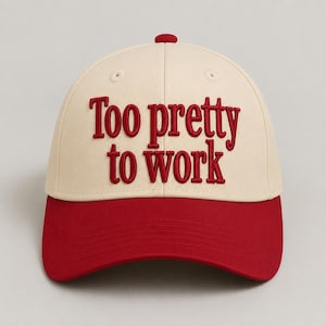 May include: A cream-colored baseball cap with a red brim and a red button on top. The front of the cap features the embroidered text "Too pretty to work" in a bold, dark red font. The cap has stitched eyelets on the crown for ventilation.
