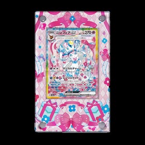 Puede incluir: Una carta de Pokémon rosa y azul con un Gardevoir EX blanco y azul con el texto "ニンフィアEX" y "270 PS". La carta está enmarcada en un borde decorativo rosa y azul con lazos y flores.