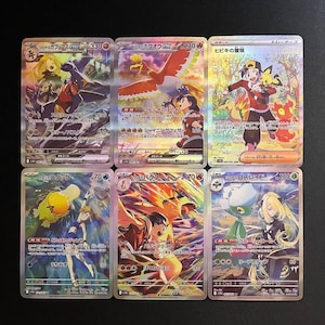 Puede incluir: Seis cartas coleccionables de Pokémon con texto japonés e ilustraciones coloridas. Las cartas presentan varios personajes y criaturas con detalles holográficos. Las cartas se muestran sobre una superficie oscura.