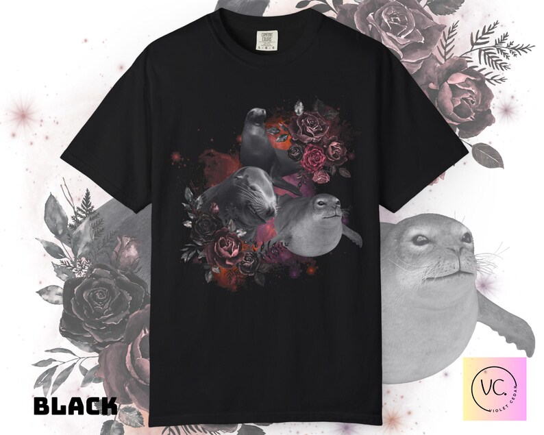 May include: Black t-shirt featuring a graphic of three seals surrounded by dark red and pink roses. The seals are in grayscale, contrasting with the vibrant floral arrangement. The word "BLACK" is printed in bold white letters.