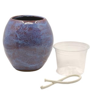 Puede incluir: Una maceta de cerámica con un esmalte azul y granate, una maceta de plástico transparente y una cuerda blanca. La maceta redonda tiene un interior oscuro y una superficie texturizada.