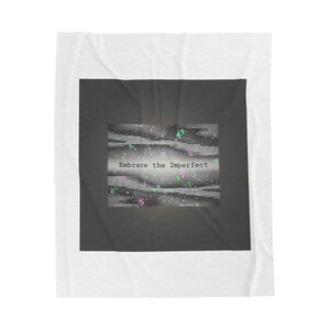 May include: A white blanket with a dark grey square in the centre. The square features the text "Embrace the Imperfect" in white, with a pixelated design in shades of grey, pink, and green.