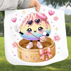 May include: A white tote bag featuring a colorful rainbow dumpling character with glittery texture, wearing heart-shaped sunglasses, a pink beret, and pink sneakers. The character stands in a bamboo steamer basket decorated with a pink bow and flowers.