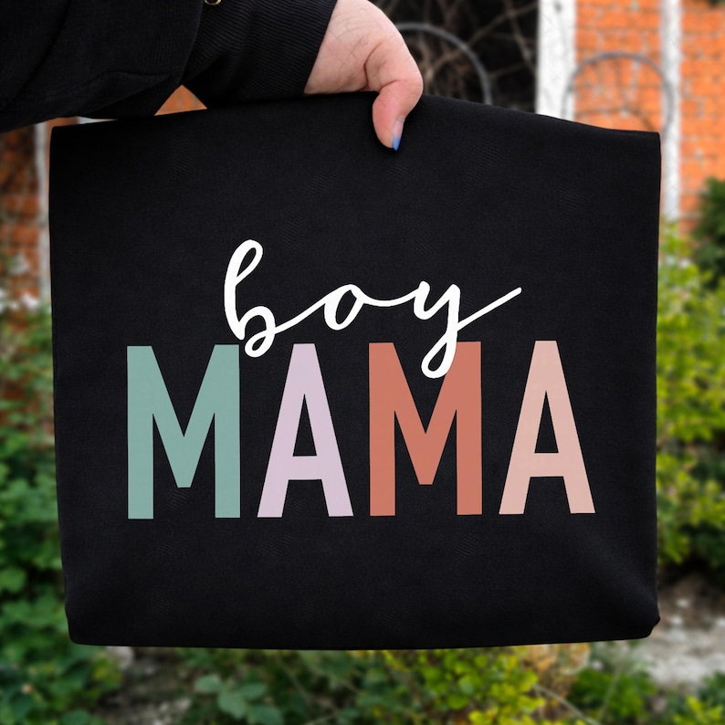 May include: Black fabric with the words "boy MAMA" printed on it. The word "boy" is in a white script font, and "MAMA" is in block letters colored teal, lavender, coral, and peach.